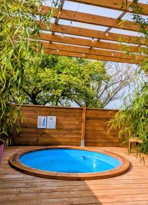 a swimming pool on a deck with a wooden fence at Le Coquelicot - Châlet avec SPA in Trainel