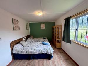 Un dormitorio con una cama y una pared verde. en Cabaña en Rio Azul Campo Base, en El Bolsón