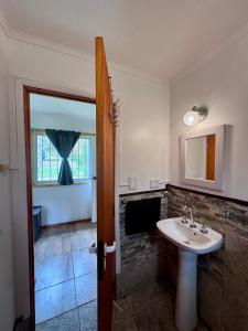 un baño con lavabo y espejo en Cabaña en Rio Azul Campo Base, en El Bolsón