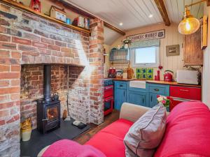 a living room with a brick fireplace and a red couch at The Cabin in Llangadog