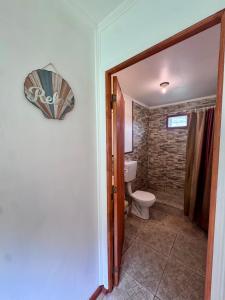 un baño con aseo y un letrero en la pared en Cabaña en Rio Azul Campo Base, en El Bolsón