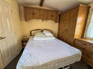 - une chambre avec un lit et des placards en bois dans l'établissement Great Dog Friendly Caravan For Hire At North Denes In Suffolk Ref 40068Nd, à Lowestoft