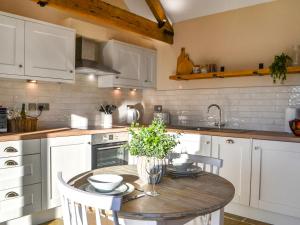 a kitchen with a wooden table and white cabinets at The Foldyard - Uk46004 in Rotsea +13 photos