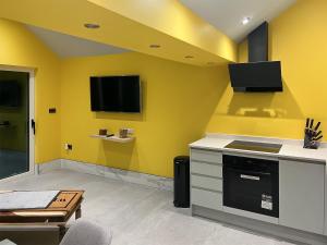 a kitchen with yellow walls and a tv on the wall at Peartree Cottage in Sheffield