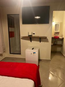 a room with a red blanket and a tv on the wall at Sítio Do Manacá in Domingos Martins