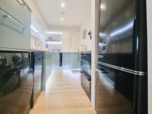 a kitchen with black appliances and a wooden floor at Mac Shack Cottage - Uk32376 in Ashen +11 photos