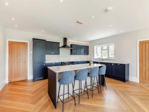 a kitchen with blue cabinets and a island with bar stools at The Cartlodge - Uk48579 in Rochford