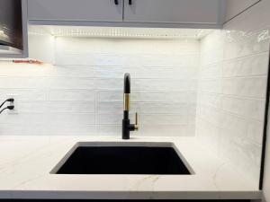 ein Waschbecken im Bad mit einer weiß gefliesten Wand in der Unterkunft Northern Nook - 2BR Suite in Calgary + 77 Fotos