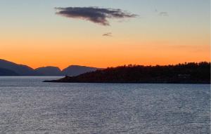 Nice Apartment In Kvalsund With Wifi في Kvalsund: جزيرة في وسط مسطح مائي عند غروب الشمس +18 صورة