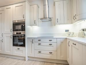 eine weiße Küche mit weißen Schränken und Geräten in der Unterkunft Copper Beech Cottage - Uk35892 in Ludchurch