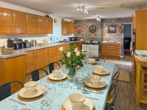 a kitchen with a table with glasses and flowers on it at Muirston Farmhouse - Uk44977 in Ochiltree