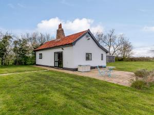 a white house with a red roof on a field at Pettingalls Farm Cottage in Great Ellingham