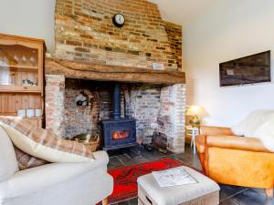 a living room with a brick fireplace and a couch at Pettingalls Farm Cottage in Great Ellingham