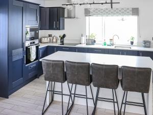 eine Küche mit blauen Schränken sowie einem weißen Tisch und Stühlen in der Unterkunft Preselli View Cottage - Uk37755 in Ludchurch