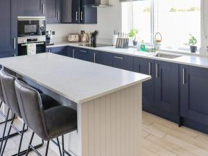 eine Küche mit blauen Schränken und einer weißen Arbeitsplatte in der Unterkunft Preselli View Cottage - Uk37755 in Ludchurch + 23 Fotos