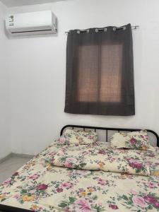 a bed with a floral comforter and a window at فيلا الزين Ab2 in Abha