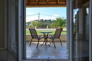 a glass door leading to a patio with a table and chairs at Villa Agiolina in Sidari