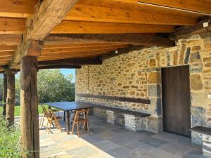 a patio with a table and chairs under a wooden ceiling at Arandi Baserria in Murueta-Orozko