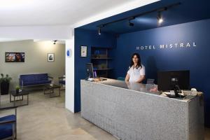 a woman is standing behind a reception counter at Hotel Mistral in Nesebar