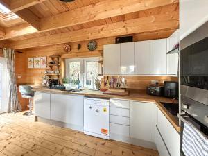 a kitchen with white cabinets and a wooden ceiling at The Cabin in Borough Green