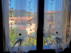 two windows with curtains with a view of a yard at Appartamento turistico Acquamarina in La Spezia