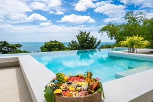 a basket of fruit sitting next to a swimming pool at Villa Ann - Contemporary Private Pool Villa near Chaweng Noi Beach in Koh Samui 