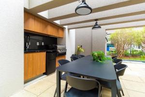 a kitchen and dining room with a black table and chairs at CGB302 - Apto com piscina e academia Bela Vista in Sao Paulo