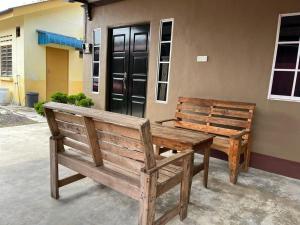 dos bancos de madera sentados frente a un edificio en Homestay ABAH, en Nibung Tebal