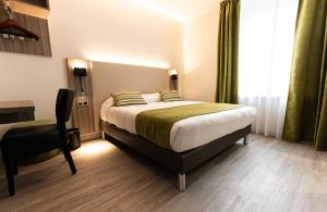 a bedroom with a bed and a desk and a chair at Hotel Cheval De Bronze in Remiremont
