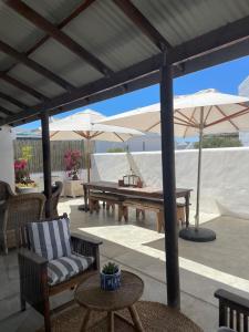 a patio with a table and chairs and umbrellas at Bougain Villa in Paternoster +31 photos