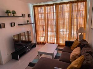 a living room with a couch and a television at Apartamento 2 Dormitorios Las Americas in Playa de las Americas