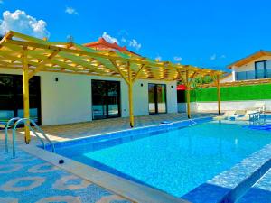 a swimming pool with a wooden pergola at Kent Villas in Demre