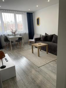 una sala de estar con un sofá y una mesa en Apartament w Centrum Faktura, en Koszalin