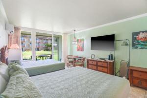 a bedroom with two beds and a television and a table at Islander on the Beach 120 - Studio in Kapaa