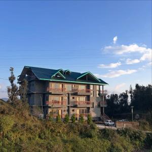 a building with a green roof on top of a hill at Shalom Hillcrest Inn in Shimla