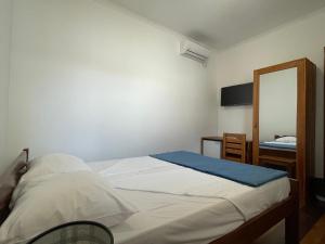 a small bedroom with a bed and a mirror at Residencial Aeroporto in São Tomé