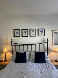 une chambre avec un lit avec quatre tableaux au mur dans l'établissement Beer Bakery Cottages - Charming Cottage Retreat - 2 mins from Beach with Car Parking space, à Beer