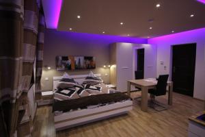 sypialnia z łóżkiem i biurkiem oraz fioletowym oświetleniem w obiekcie Apartmenthaus Wertheim w mieście Wertheim