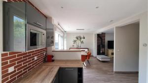 a kitchen and living room with a brick wall at Location Cosy Paris - villa Emeraude in Sainte-Geneviève-des-Bois