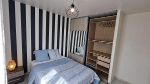a bedroom with a bed and a striped wall at Location Cosy Paris - villa Emeraude in Sainte-Geneviève-des-Bois