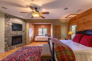 una camera da letto con camino e un letto con ventilatore a soffitto di A High Country Retreat a Boone Altre 73 foto