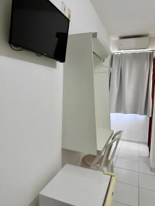Una habitación con una mesa y un televisor en una pared. en Hotel Ideal, en Jequié
