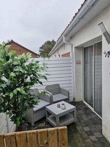 a patio with a couch and a table and a fence at Studio avec jacuzzi , terrasse amenagée et wifi à Westrehem in Westrehem