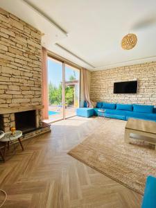 a living room with a blue couch and a brick wall at Villa sunset Moulay in Essaouira