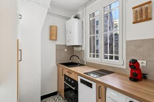 a small kitchen with a sink and a refrigerator at Luxury Paris Apt, Metro 4 & RER B, 6 guests, CDG Access in Paris