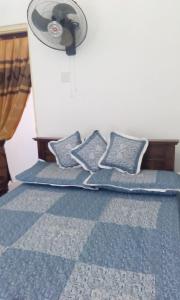 1 dormitorio con 1 cama azul con almohadas y ventilador en Two rooms apartment, en Moratuwa