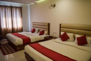 a hotel room with two beds with red pillows at Pam Green in Mussoorie