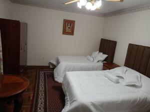 a hotel room with two beds with white sheets at La casita del abu Alfredo in Cochabamba
