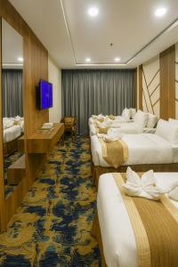 メッカにあるMoro Ala Hotel Makkah by Moroのベッド4台とテレビが備わるホテルルームです。