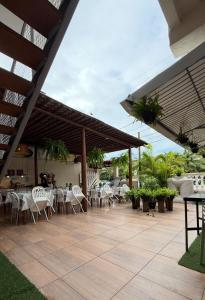 a patio with white tables and white chairs at Pousada Mel in Praia do Forte +55 photos